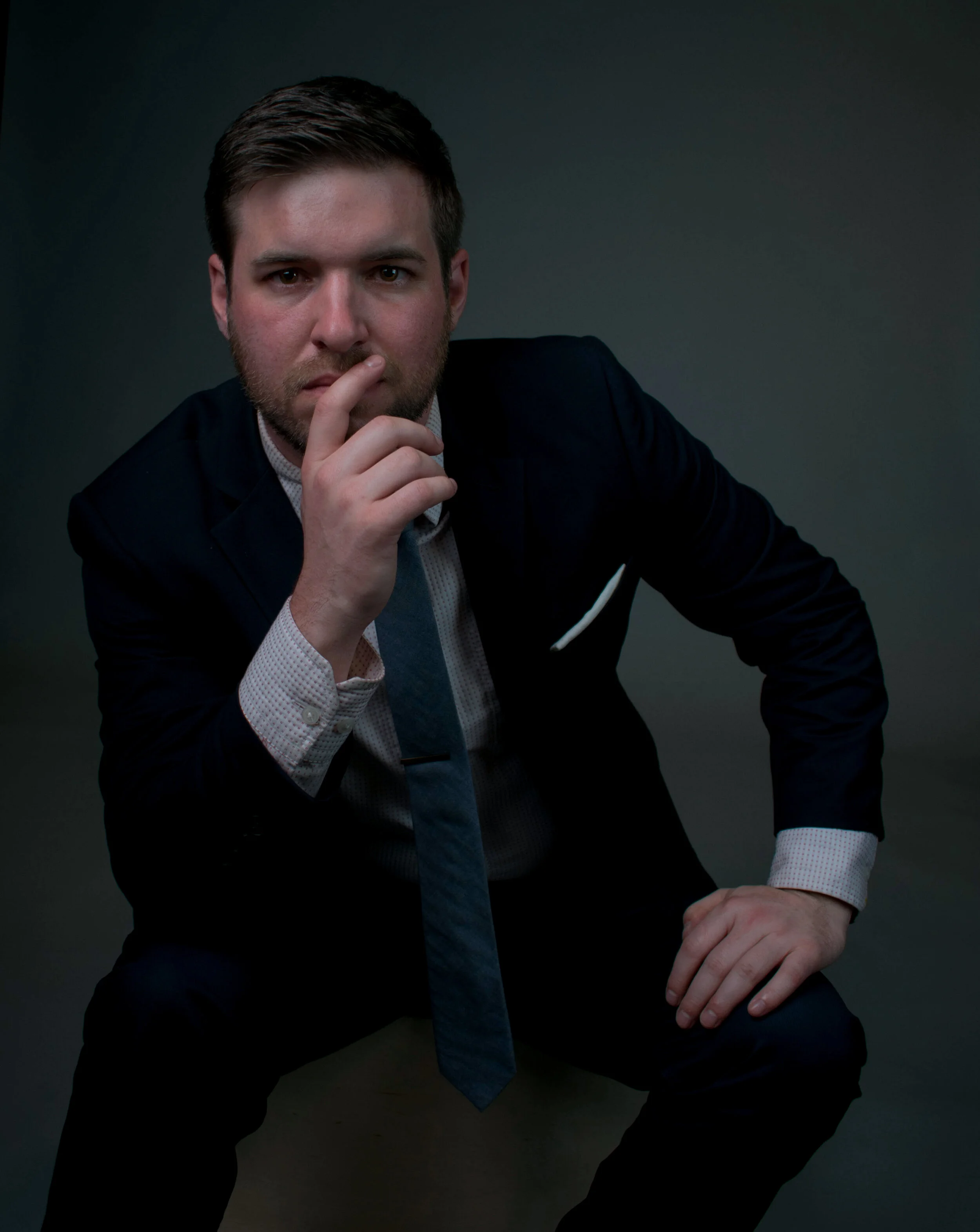 The author in a contemplative pose wearing a dark blue suit.