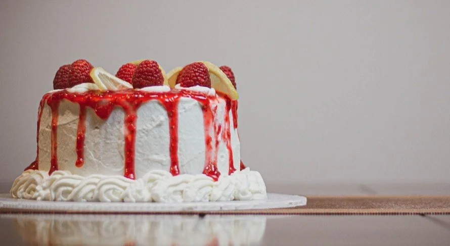 A close-up of a blue-frosted cake with a slice removed, revealing white cake and red jam layers. The image represents the sensory "30-degree shift" described in the story.