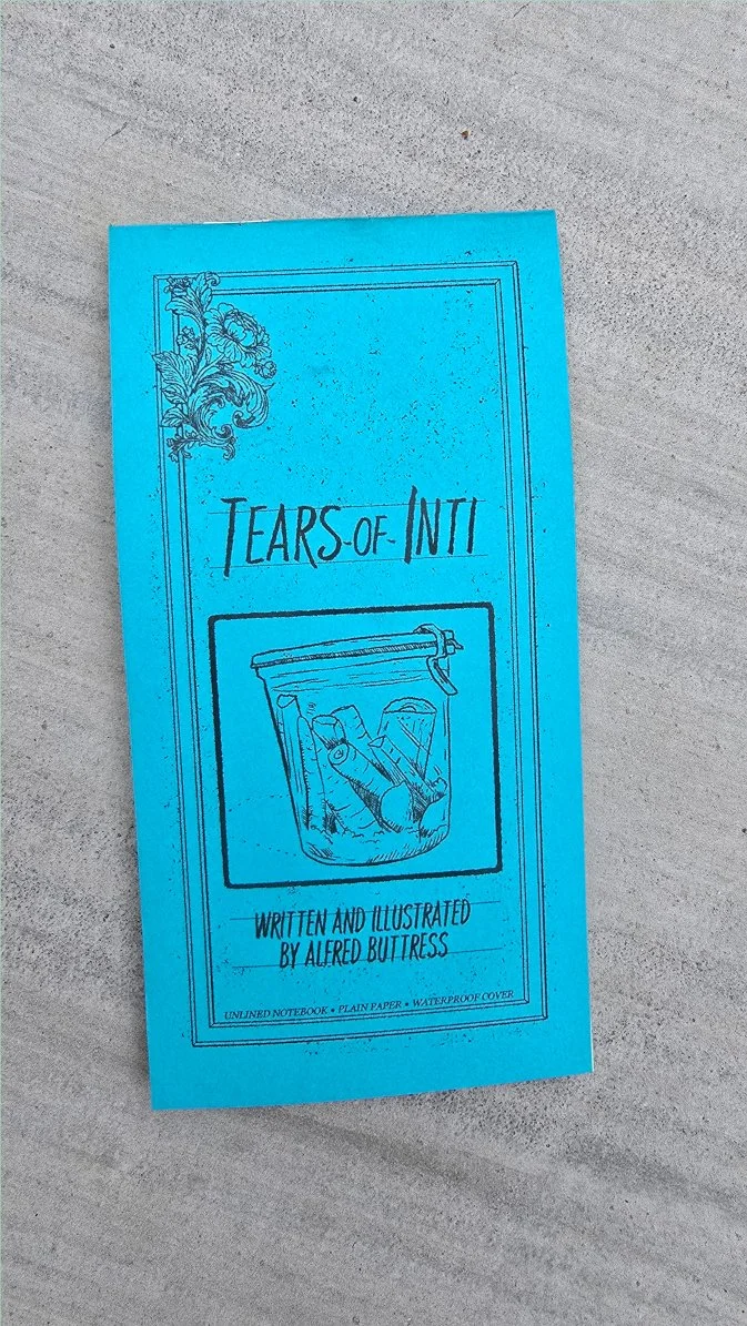 Photograph of the printed Tears of Inti zine lying on concrete, showing the turquoise cover with an illustration of a fermentation jar filled with carrots.`