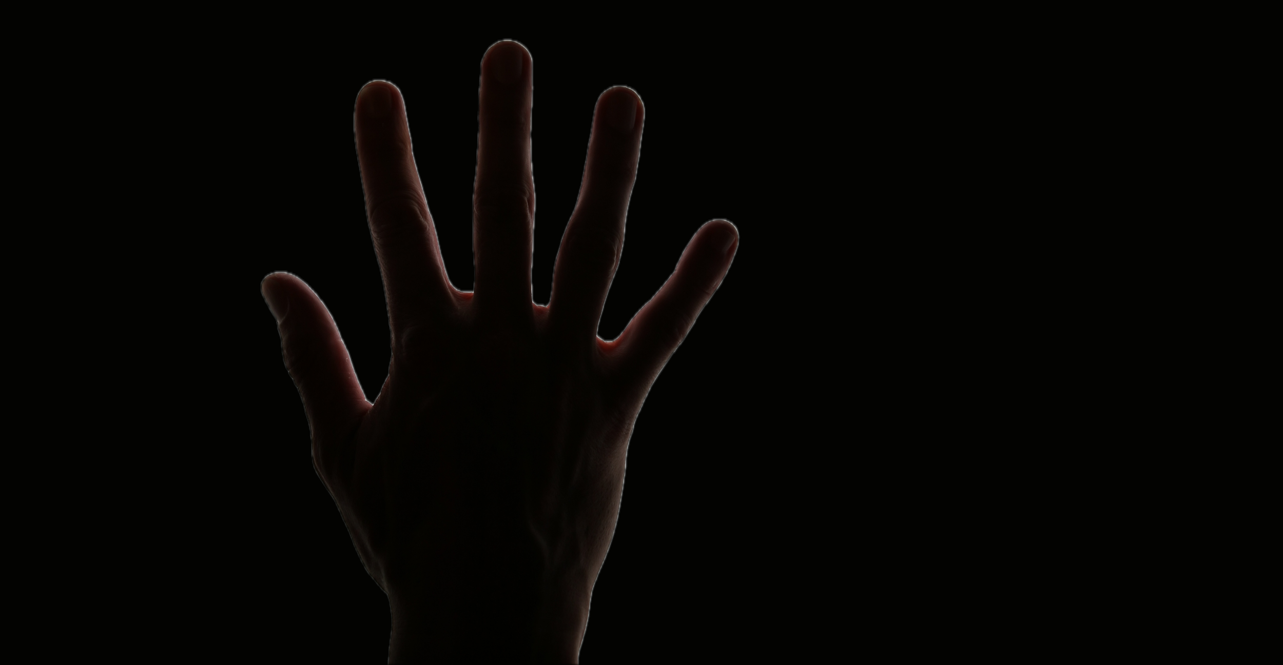 Silhouetted hand reaching upward against a black background with faint red light outlining the fingers