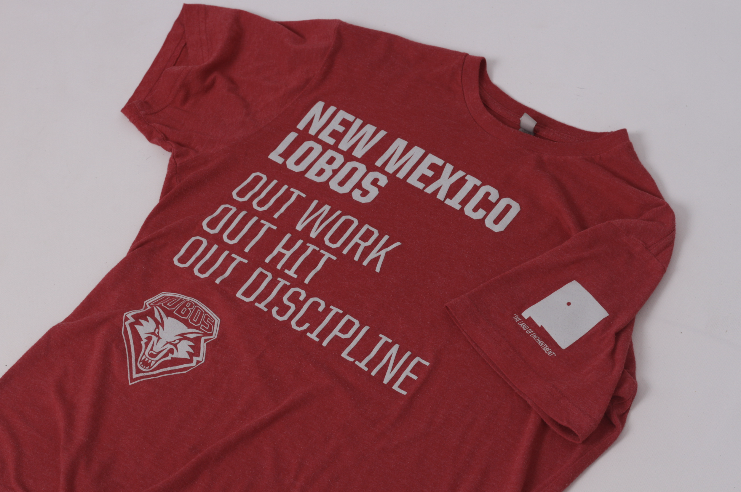 Red T-shirt with white text "New Mexico Lobos" "Out Work" "Out Hit" "Out Discipline" and University of New Mexico wolf logo