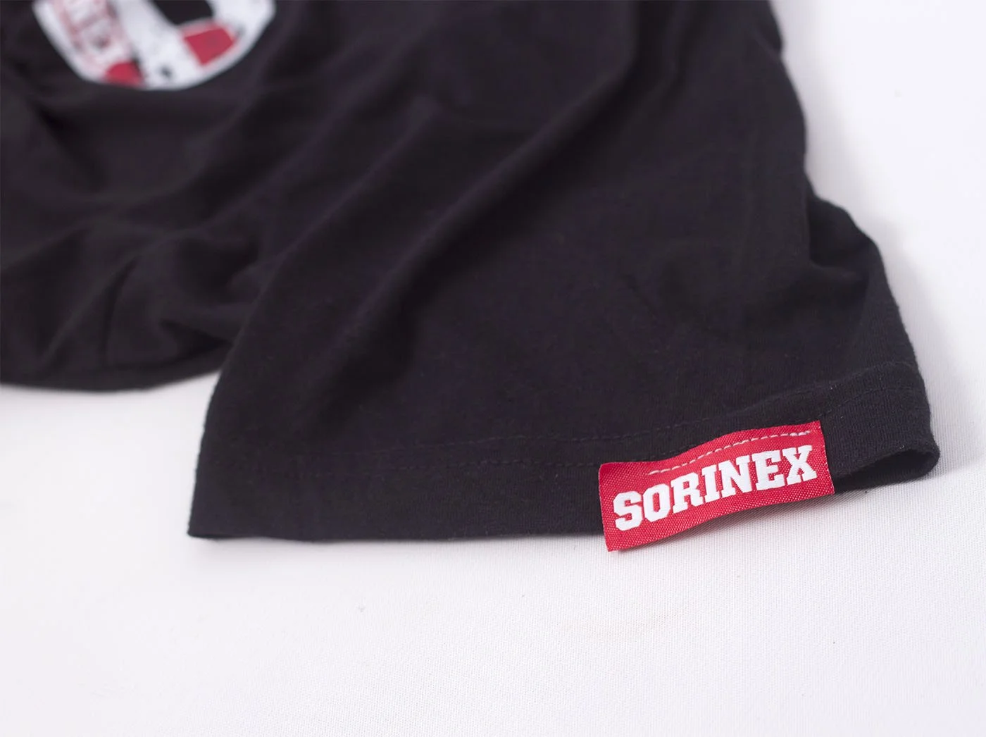 A black sleeve of Sorinex T-Shirt showing with a custom red hem-tag that says 'SORINEX' in white letters.