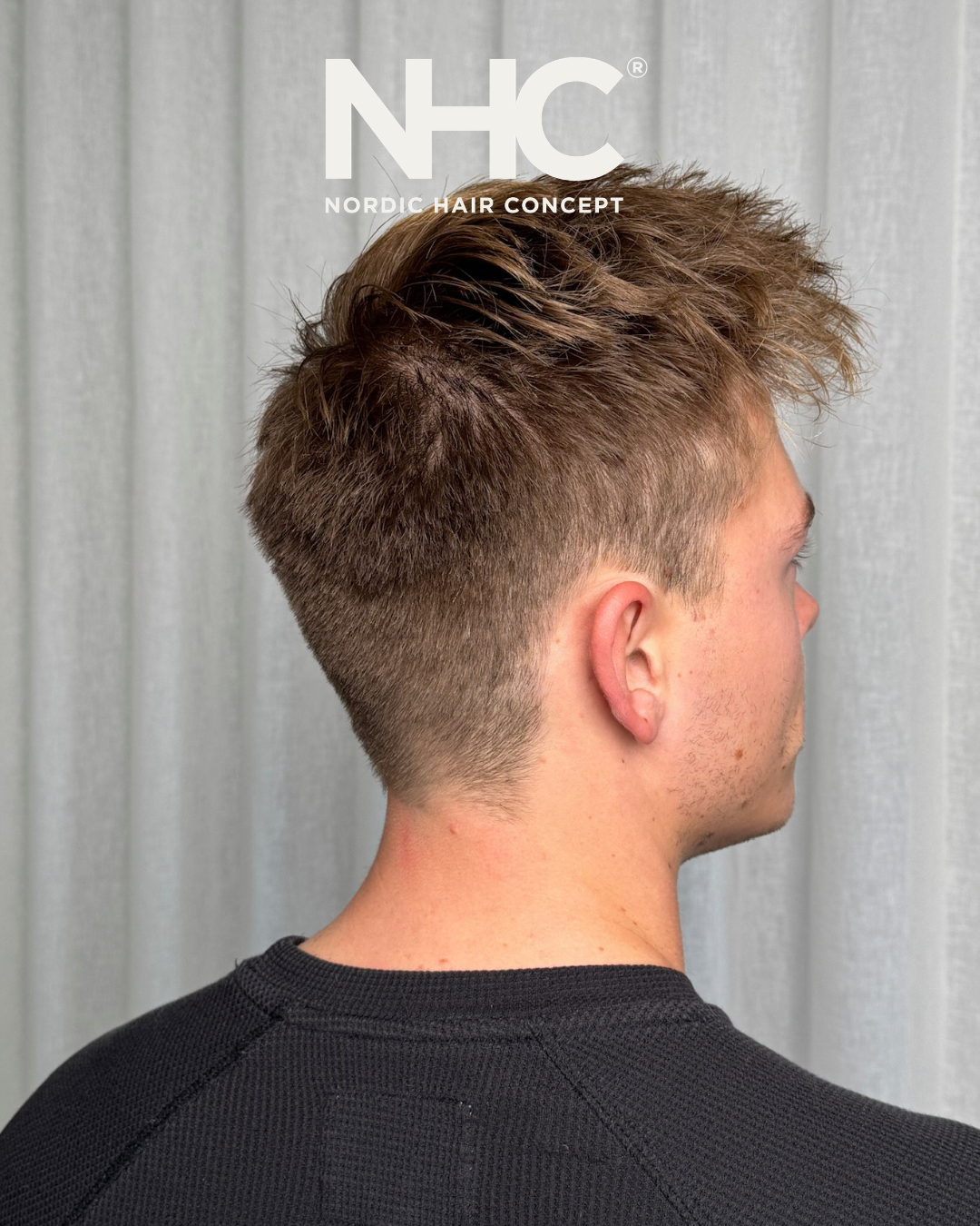 Sideview af en mand med en modern, kortklippet frisør og længere, stylet hår på toppen.