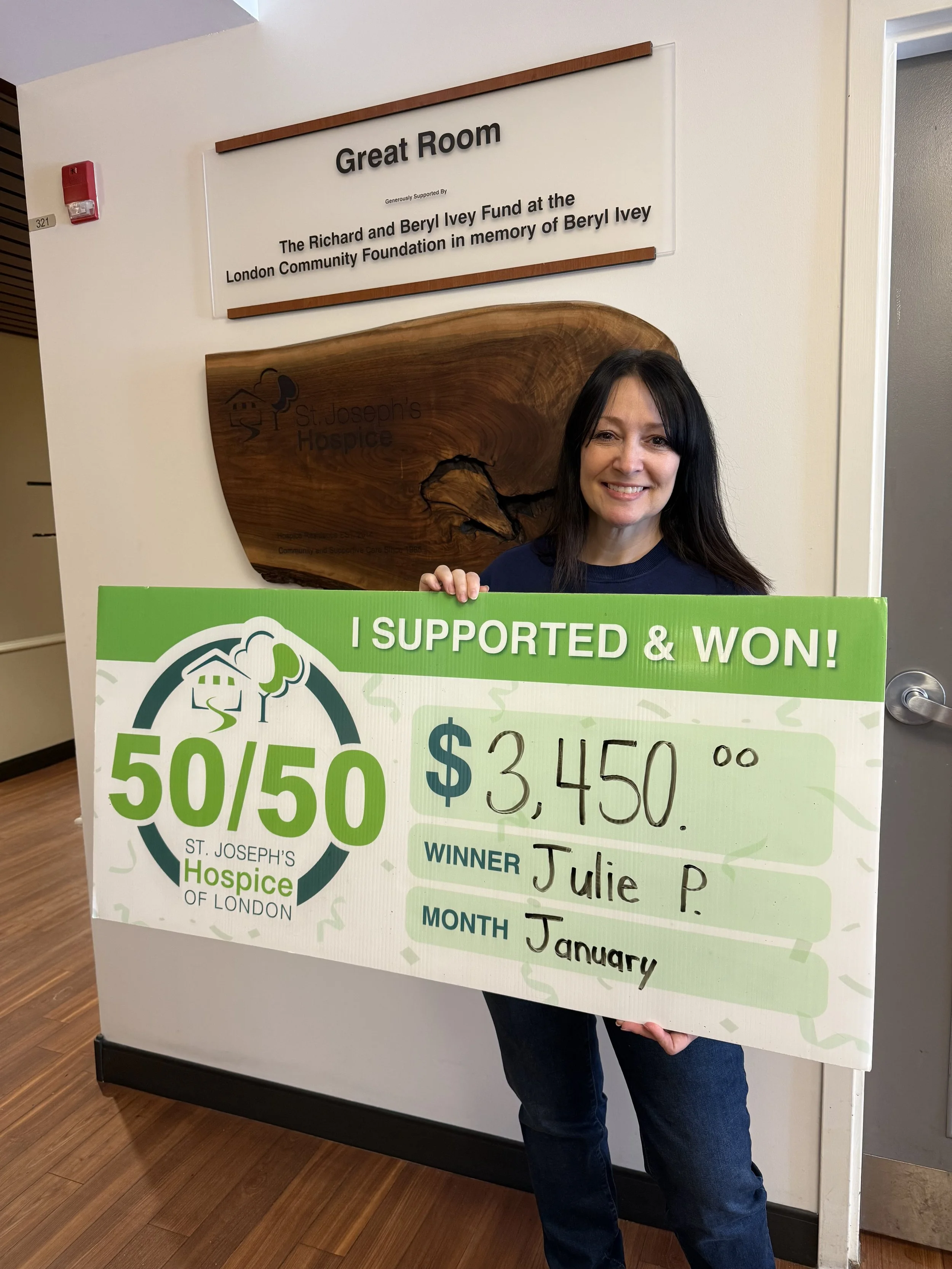 Julie holding a 50/50 winner cheque