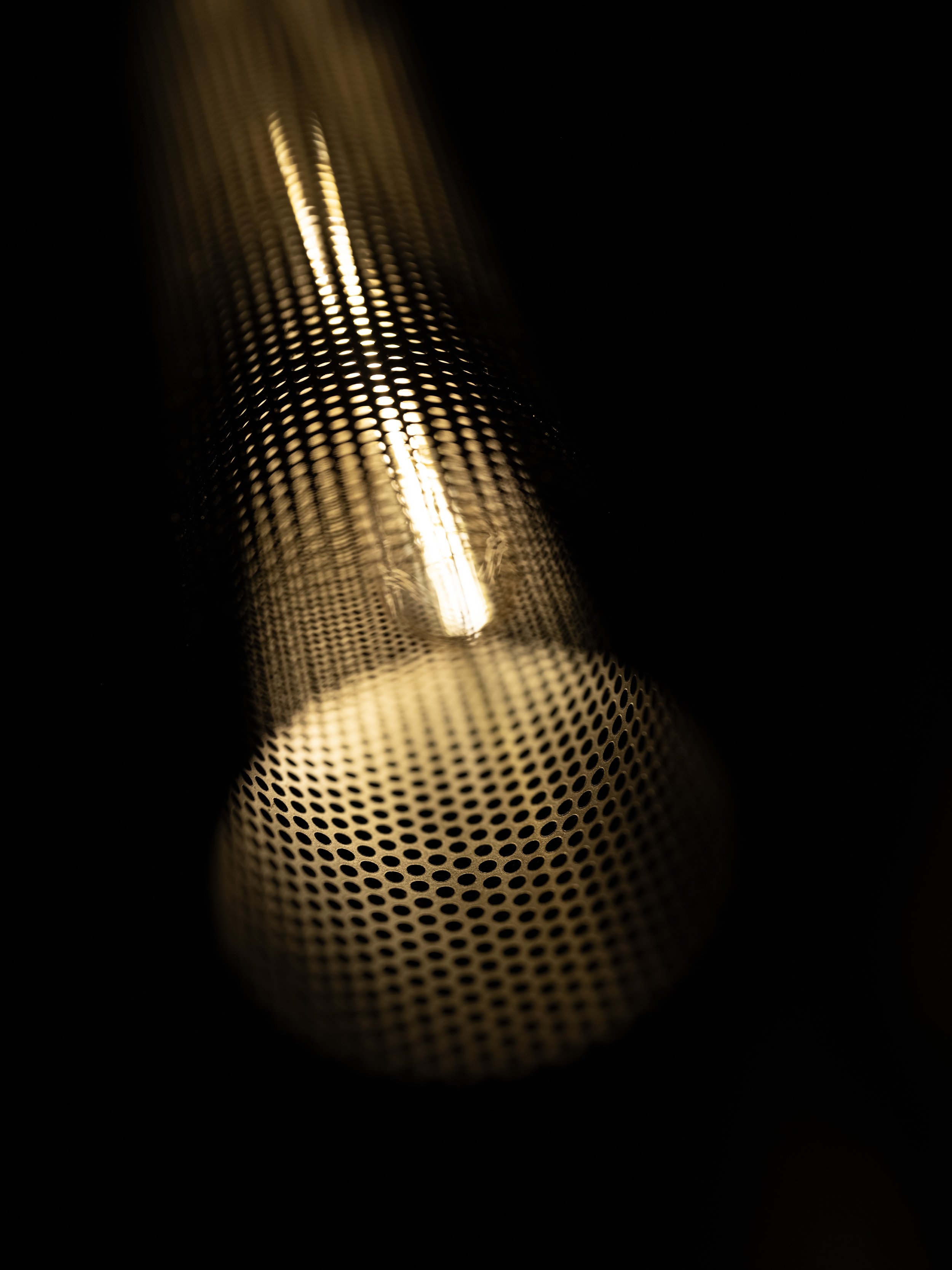 Close-up of perforated metal tube with light passing through
