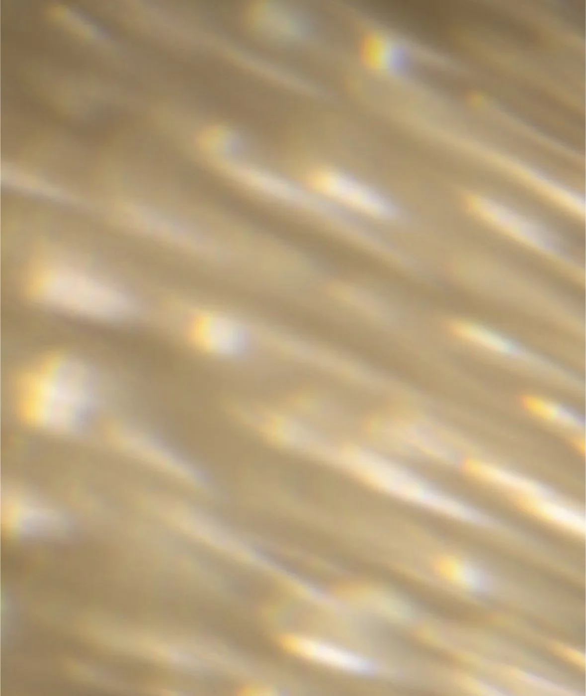 Blurred, gold-colored surface with rainbow-colored reflections.