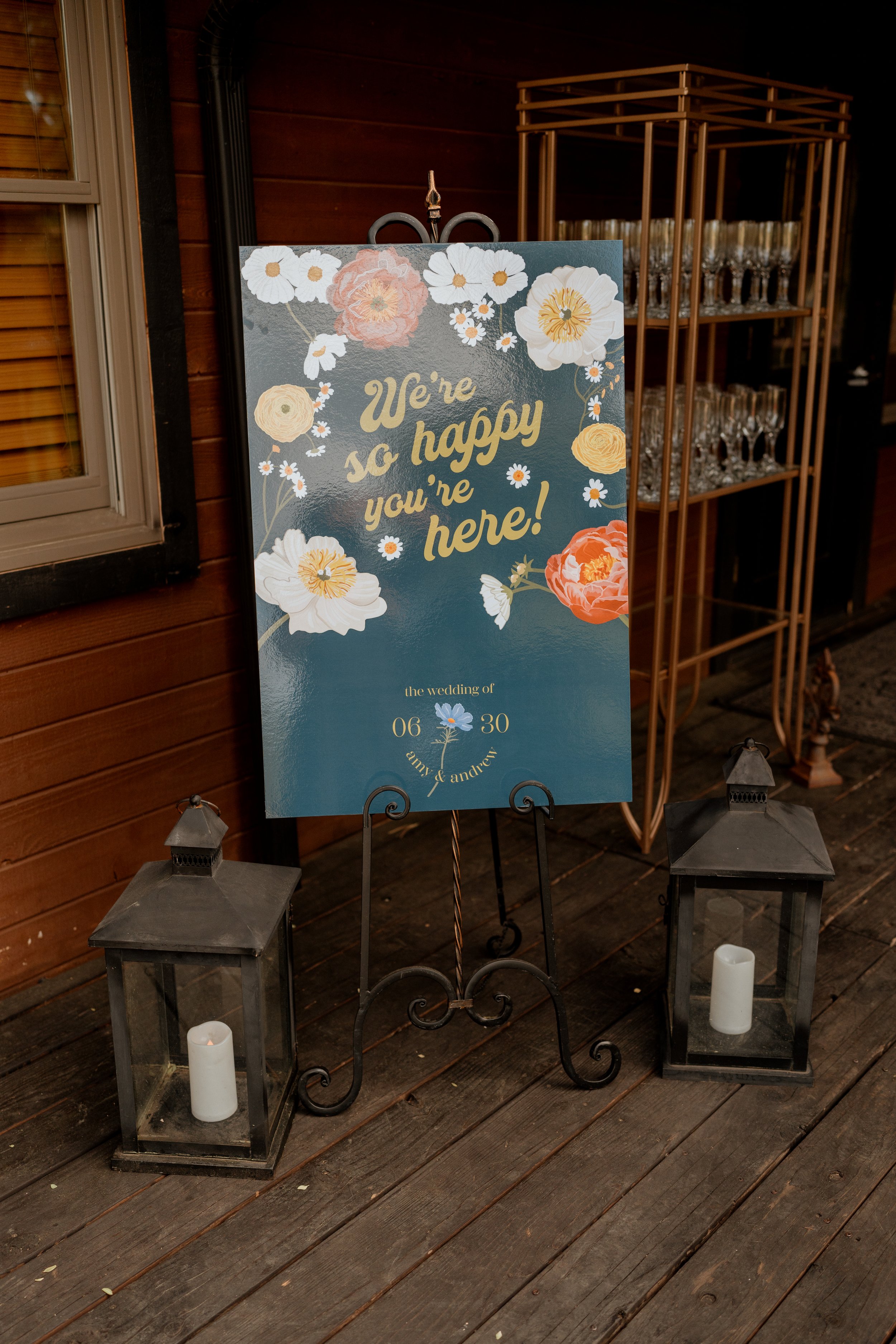 Wedding welcome sign with floral design and candles on lanterns.