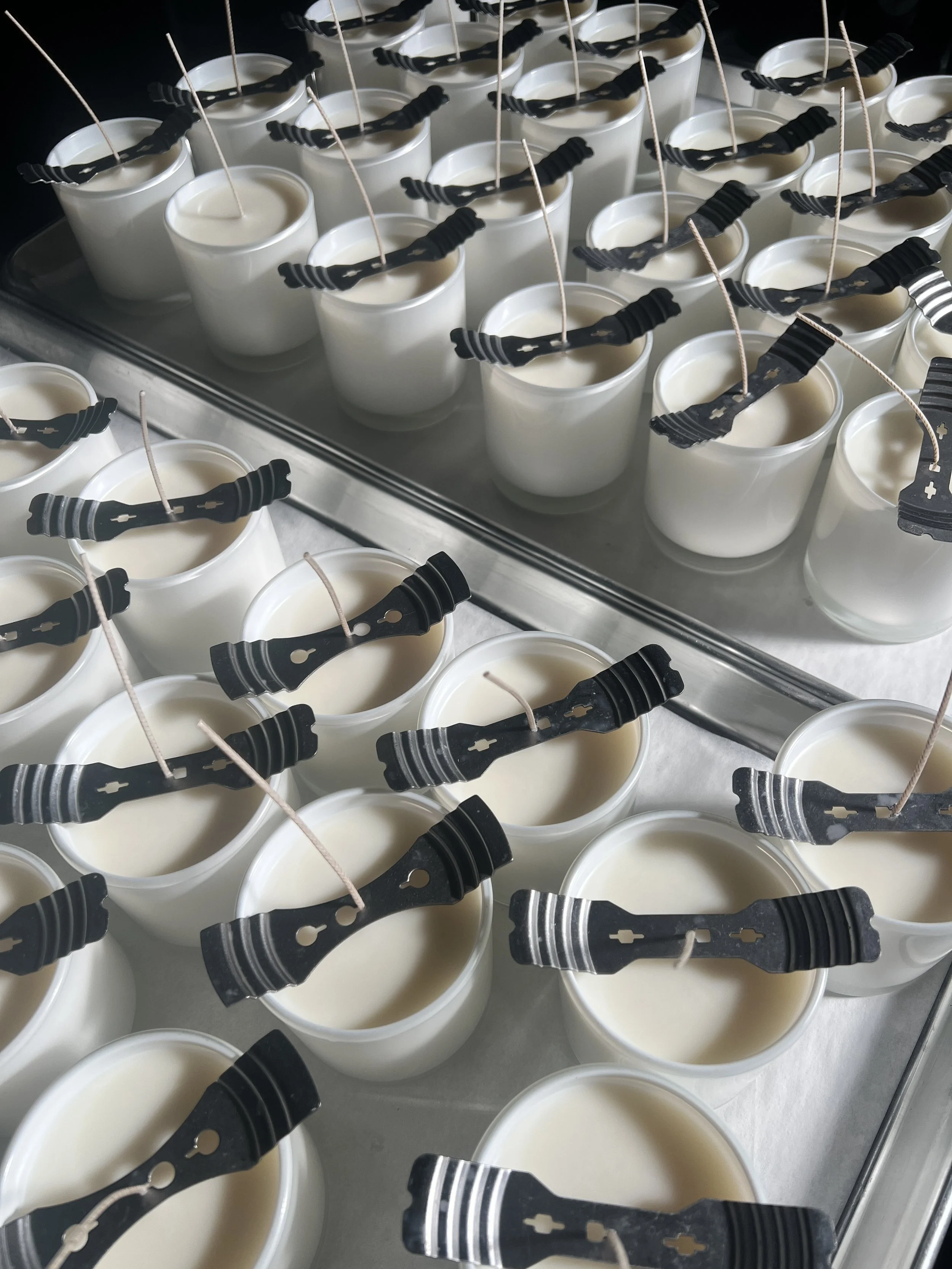 Wick setting and alignment in progress during custom candle manufacturing using white containers