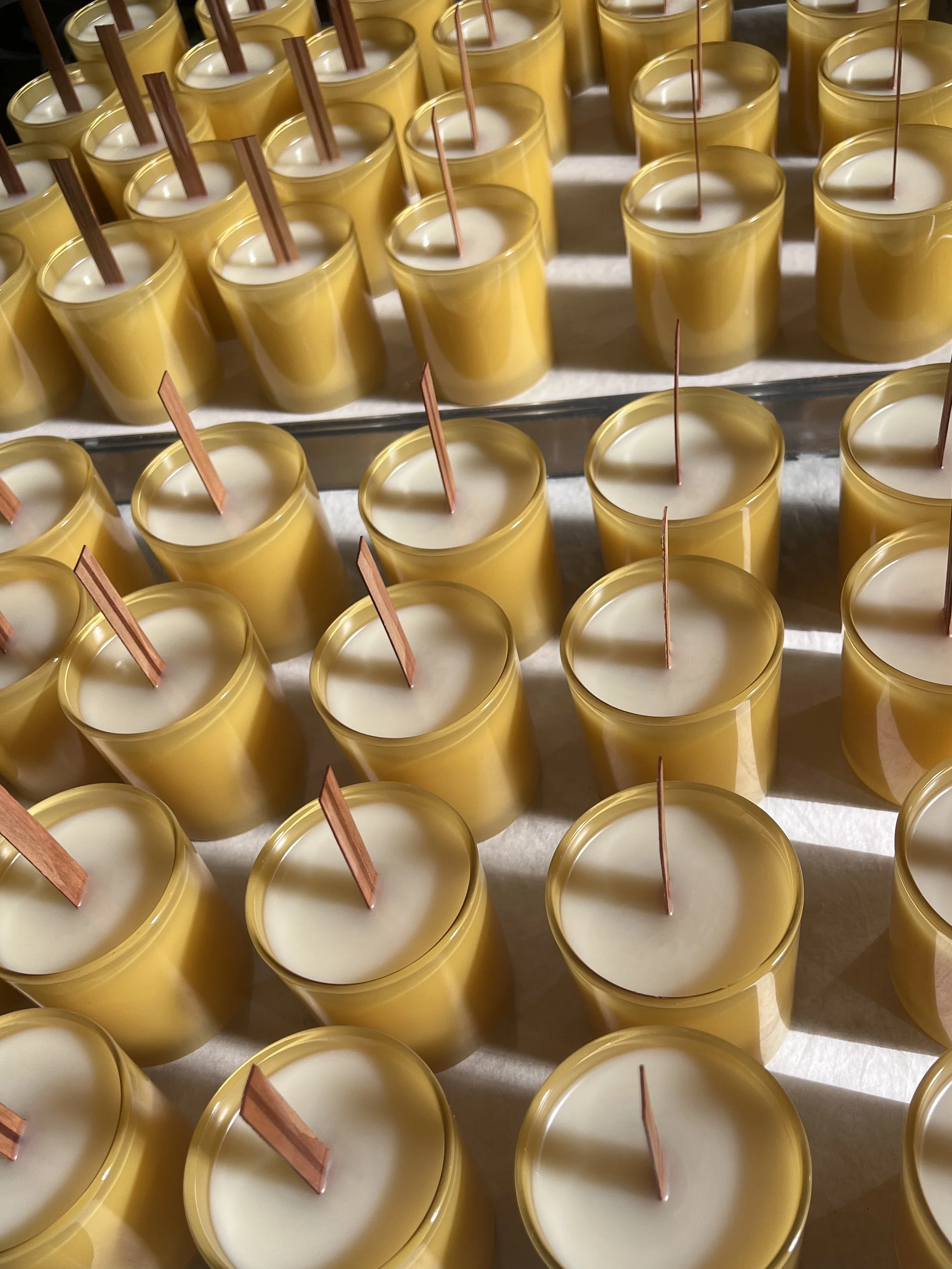 Hand poured candles with wooden wicks curing in gold vessels during private label production