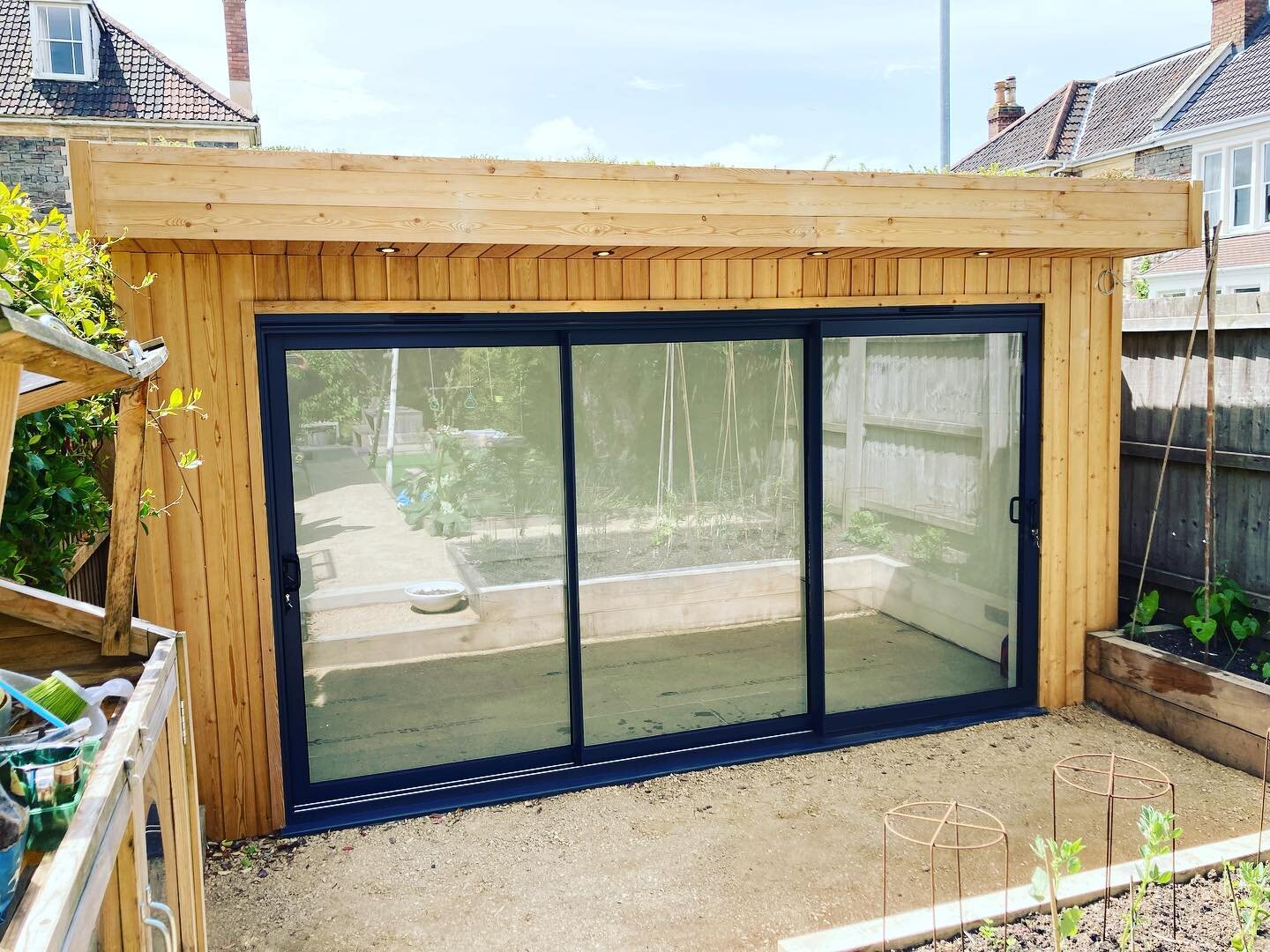 Siberian larch clad garden room with triple track sliding door, sun tunnel roof lights and sedum green roof 👌