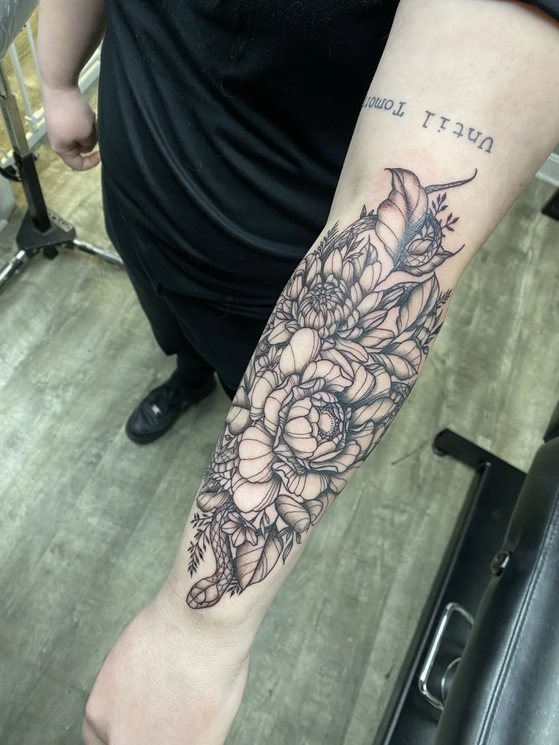 Black-and-grey snake and flowers forearm tattoo by Liz House