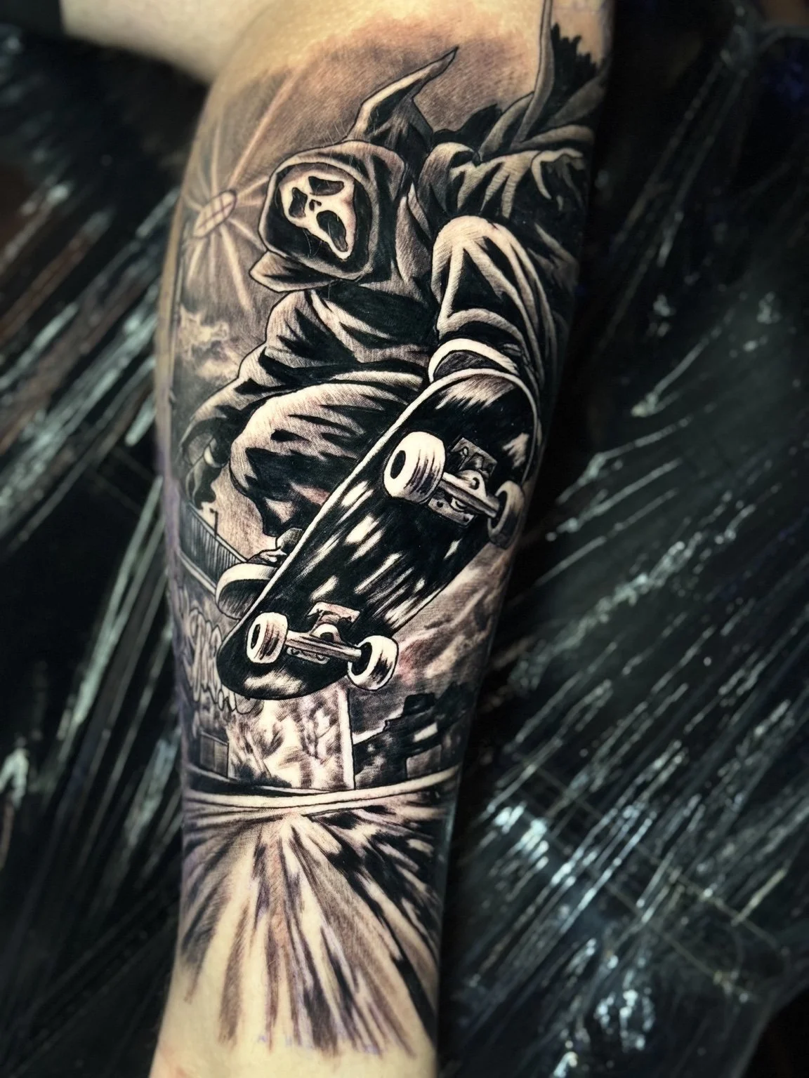 Black-and-grey Ghostface skateboarding tattoo by Scott Flanders