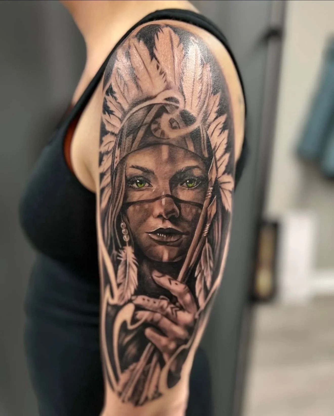 Realistic portrait with feathers and green eyes tattoo by Ren Giang
