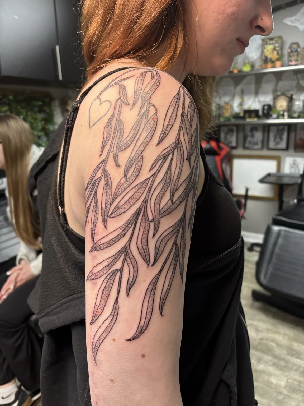 Fine-line leafy shoulder tattoo by Anna Small