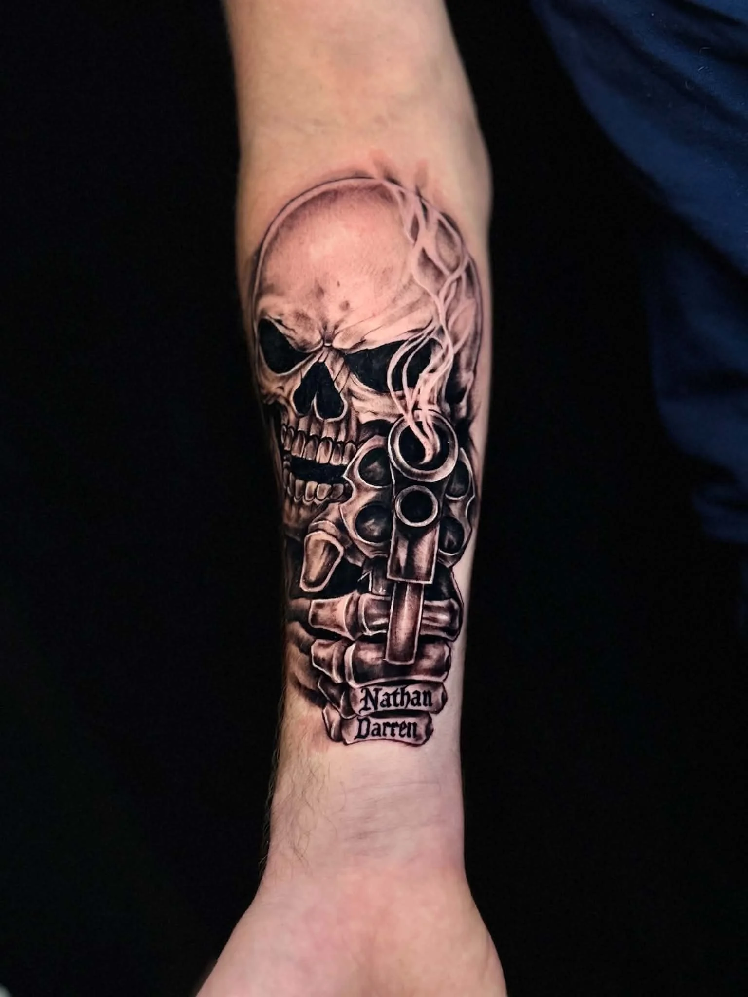 Black-and-grey skull and revolver tattoo by Hailee Rivera