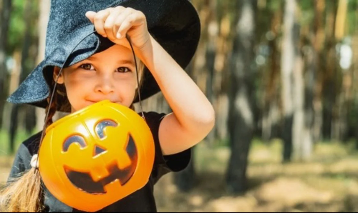 Girl dressed as Halloween witch with pumpkin basket