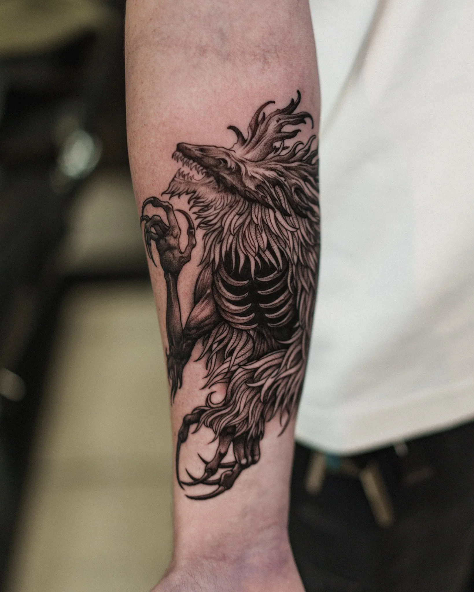 Black ink tattoo of a mythical creature with a wolf-like head and a mane, its the character the Cleric Beast from the FromSoft game Bloodbourne. Dark fantasy inspired tattoo by Jason James Smith
