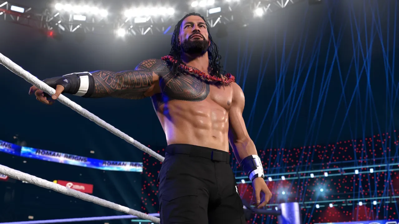 WWE 2K26 gameplay screenshot featuring a realistic character model of Roman Reigns standing in the wrestling ring, wearing a red Ula Fala and black cargo pants under bright arena lights.