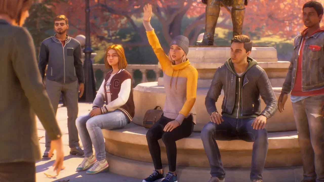 A group of young adult characters gathered around a campus fountain in Life is Strange: Reunion, with one woman in a yellow hoodie raising her hand.