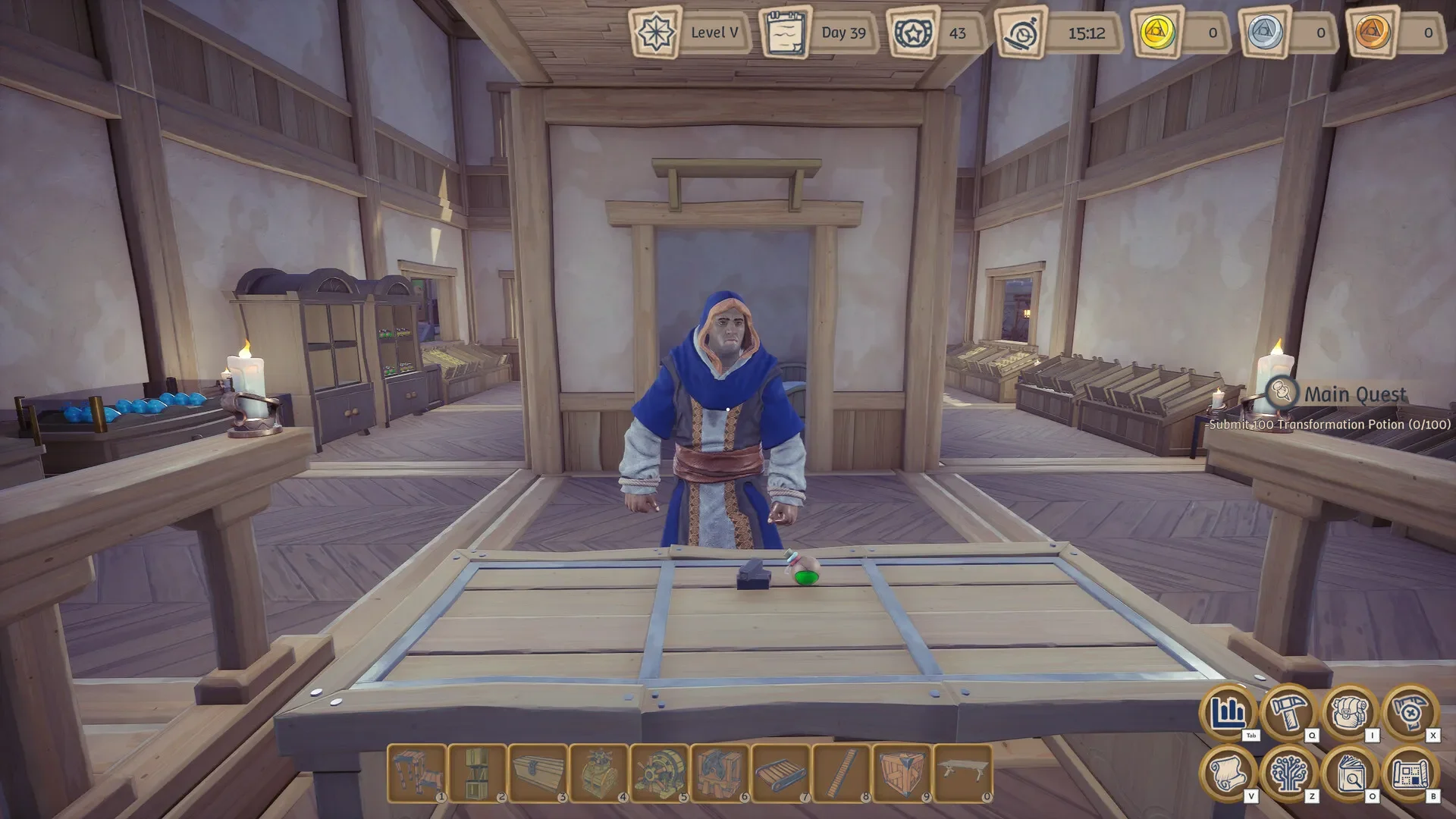 A first-person view in Alchemy Factory showing the player character, an alchemist in blue robes, standing behind a wooden crafting table with a potion vial on it, inside a workshop filled with ingredient storage bins and furniture.