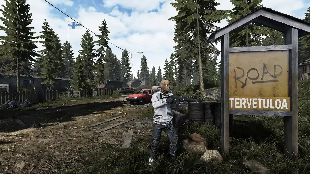 Masked survivor holding an assault rifle next to a "Tervetuloa" sign in a rural Finnish forest setting from the survival game Road to Vostok.