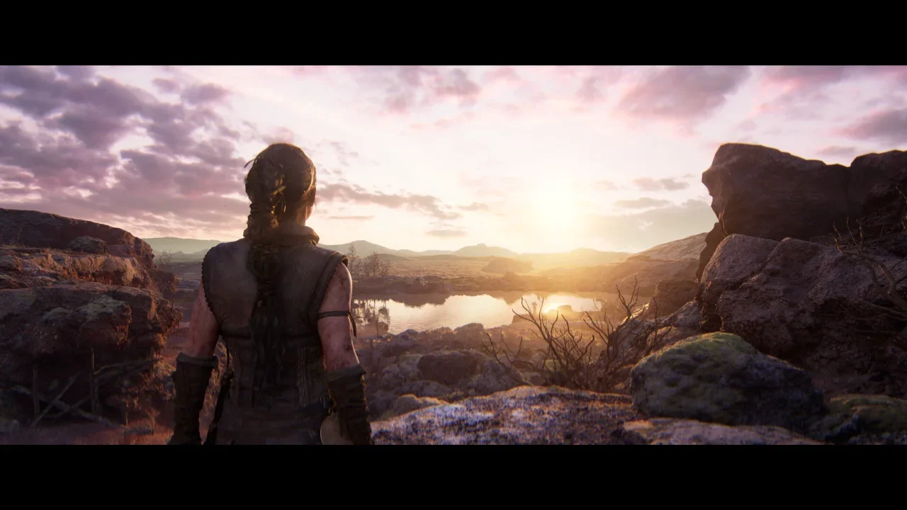 Senua overlooking a vast, rocky landscape at sunrise in a cinematic gameplay screenshot from Senua's Saga: Hellblade II.