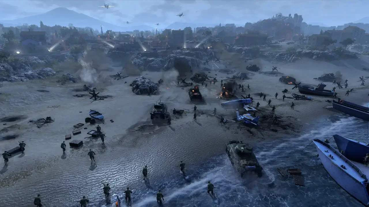 Company of Heroes 3 screenshot showing Allied troops assaulting a contested Mediterranean beachhead at dusk, featuring wrecked landing craft, burning tanks, and fighter planes overhead.