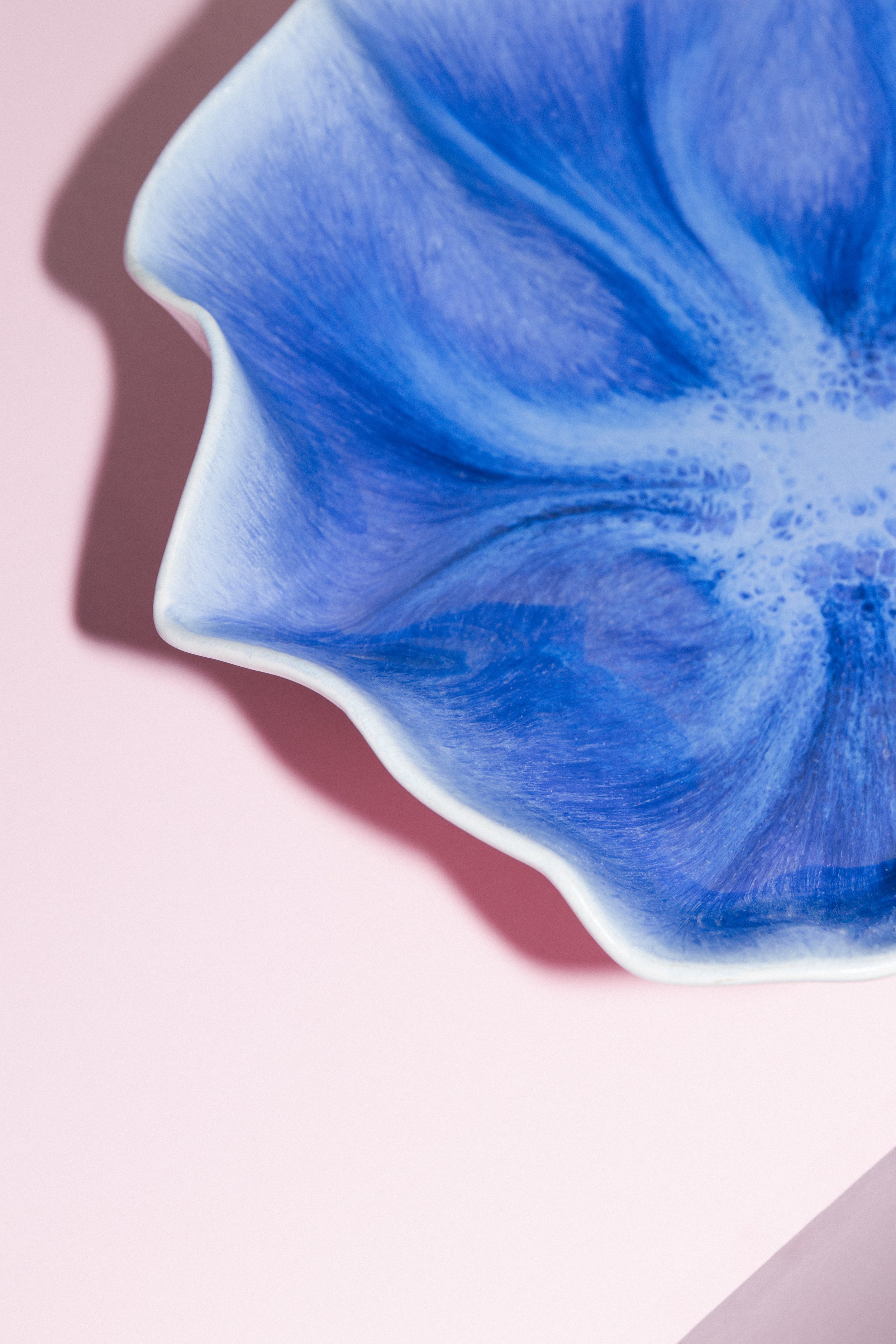 Blaue und weiße Marmorierte Keramikschale auf rosa Hintergrund mit Schatten.