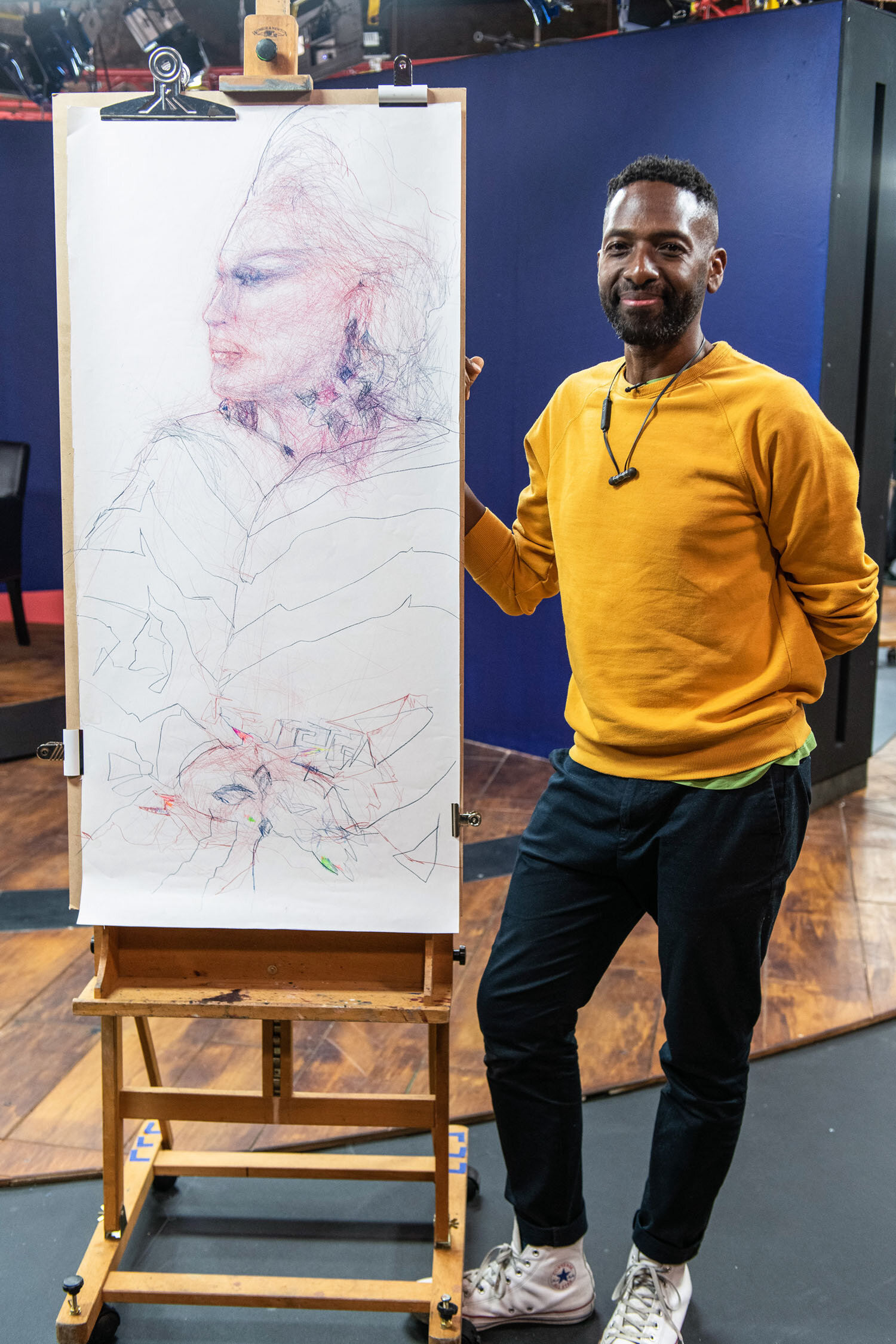 Curtis Holder stood with his winning portrait of Ru Paul's Drag Race UK star The Vivienne drawn during Heat 2 of Portrait Artist of the Year, Series 7