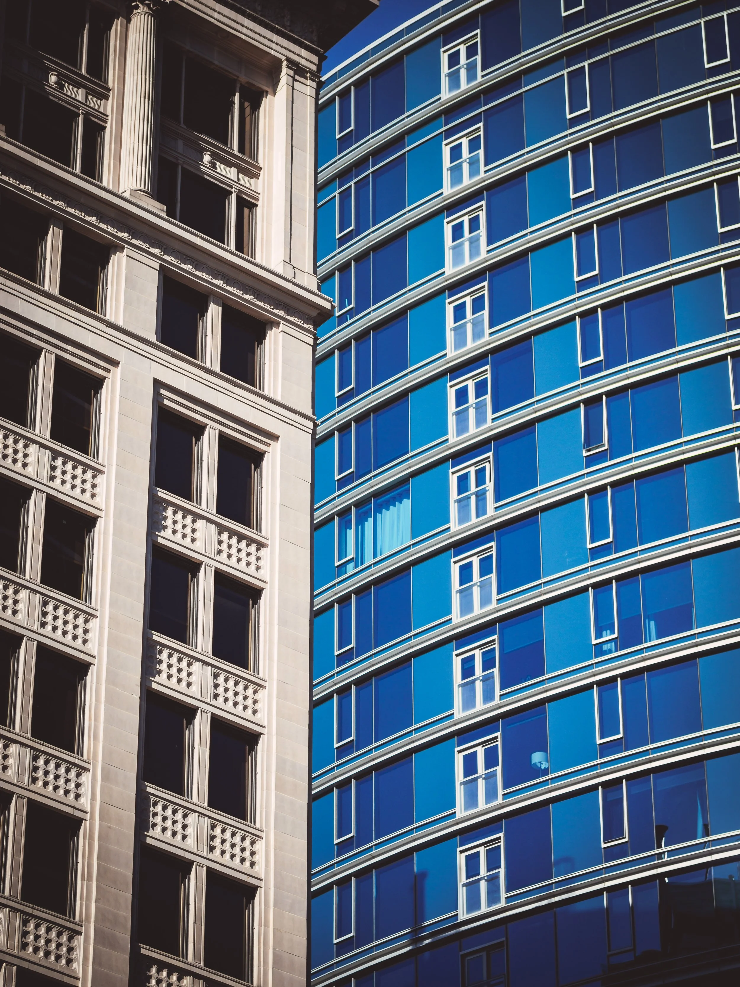 A blue building with glass windows next to a stone building in Salt Lake City Utah