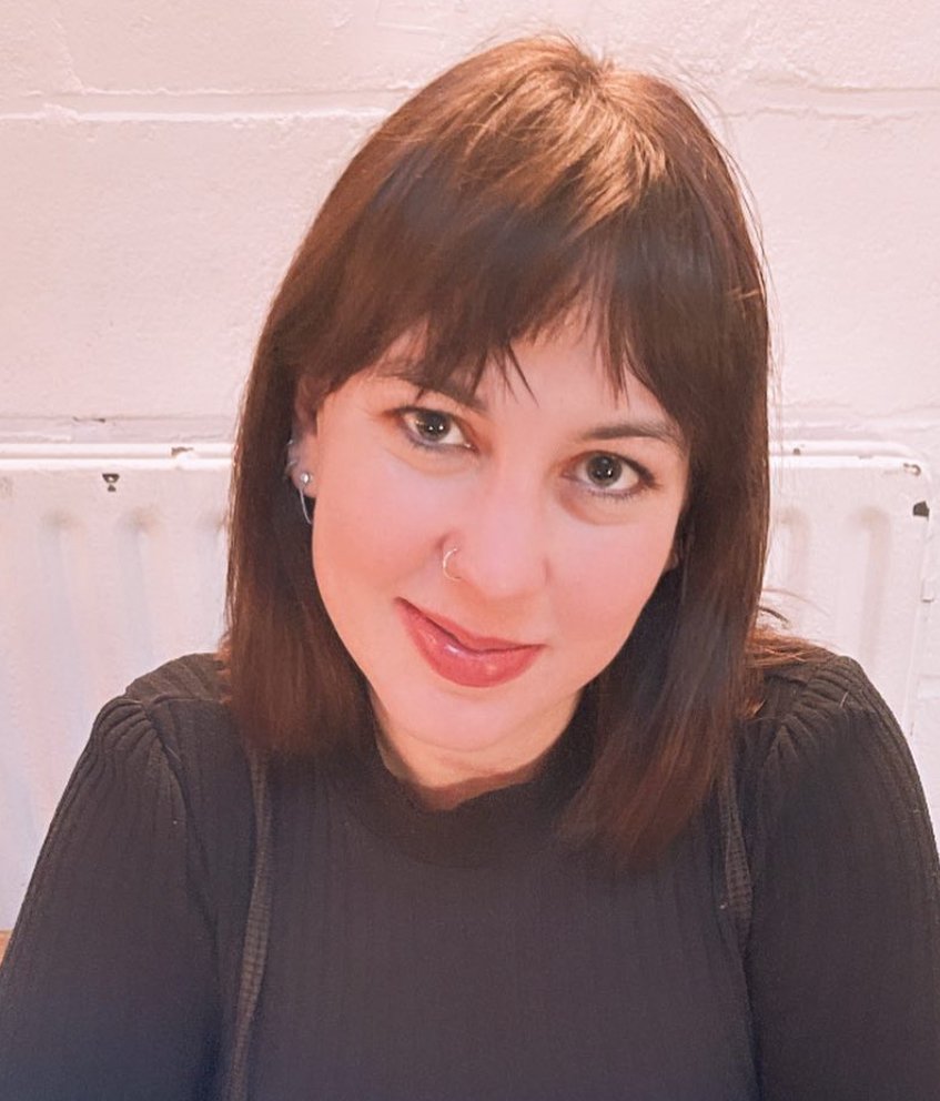 Anna Sandy-Elrod standing in front of a white brick wall.