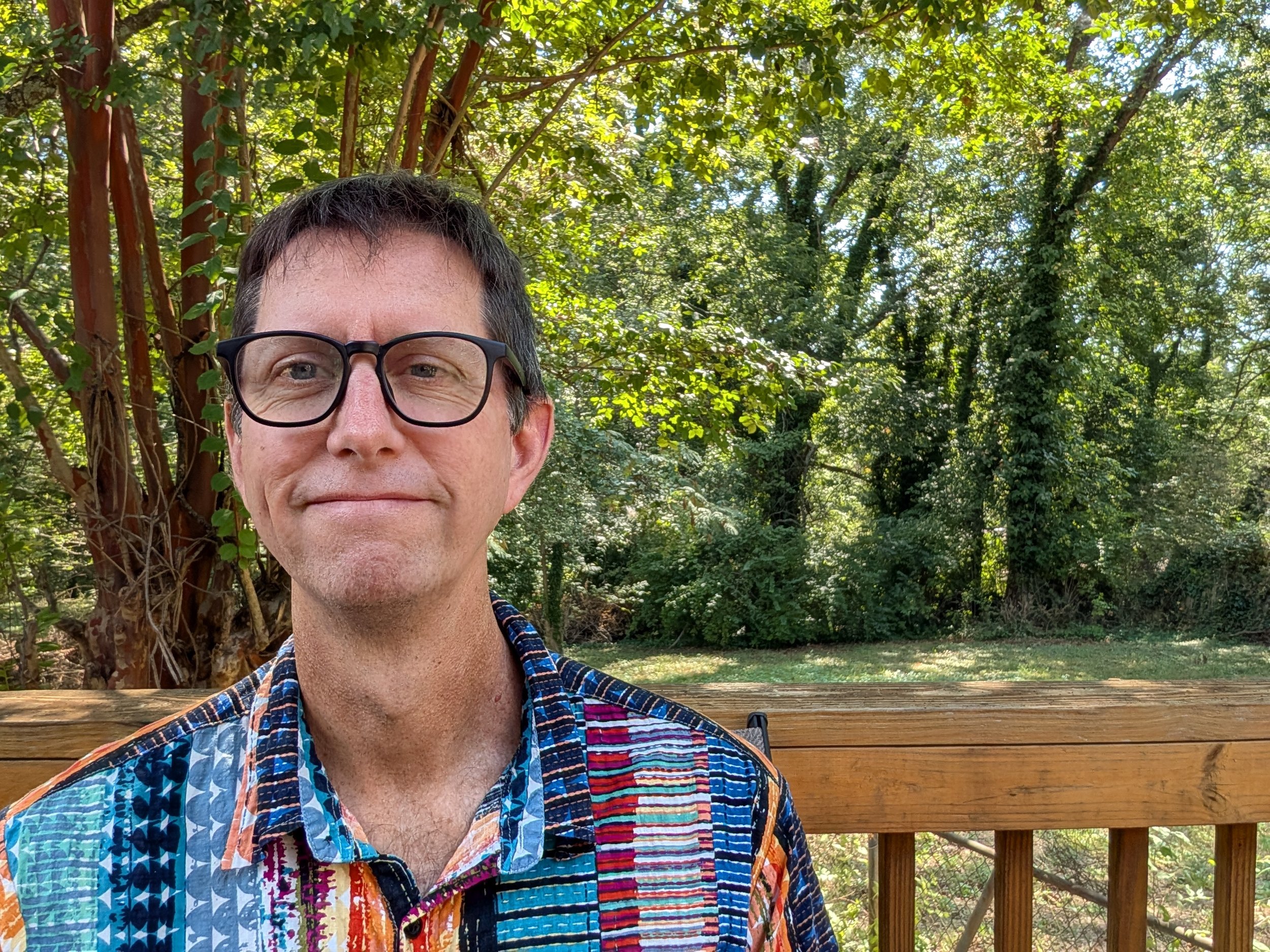 Pete Rorabaugh standing in front of a brown railing and green trees.