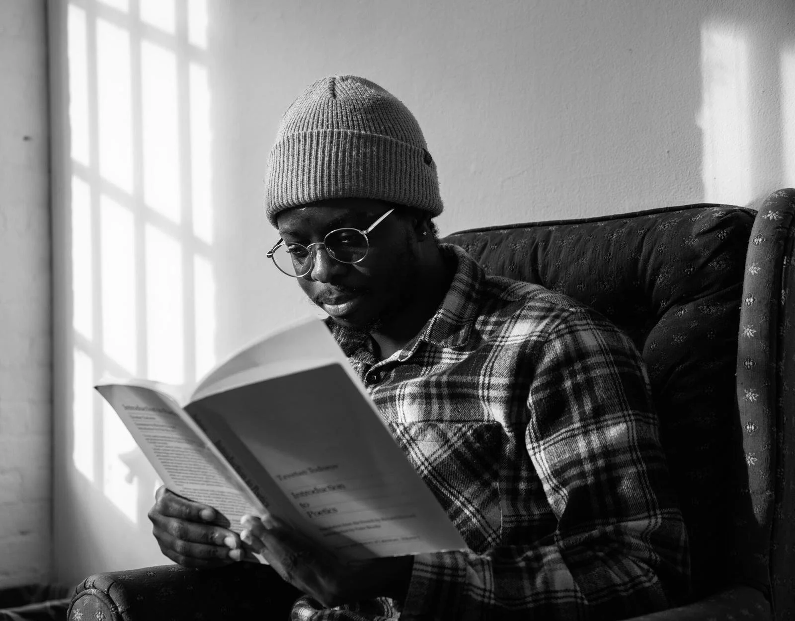 O-Jeremiah Agbaakin sitting in a chair and reading a book.