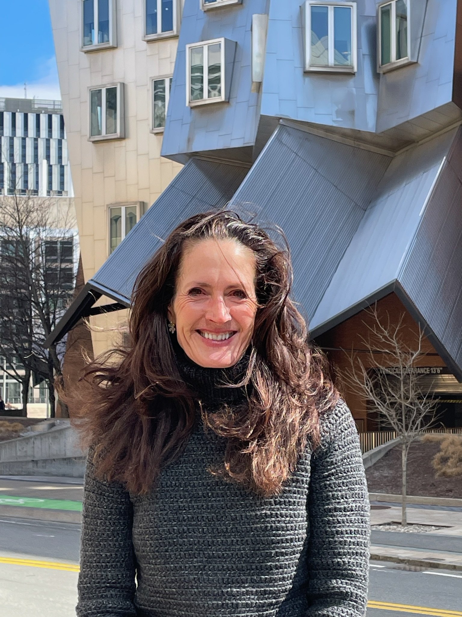 Kristin Rajan standing in front of a brown and gray building.