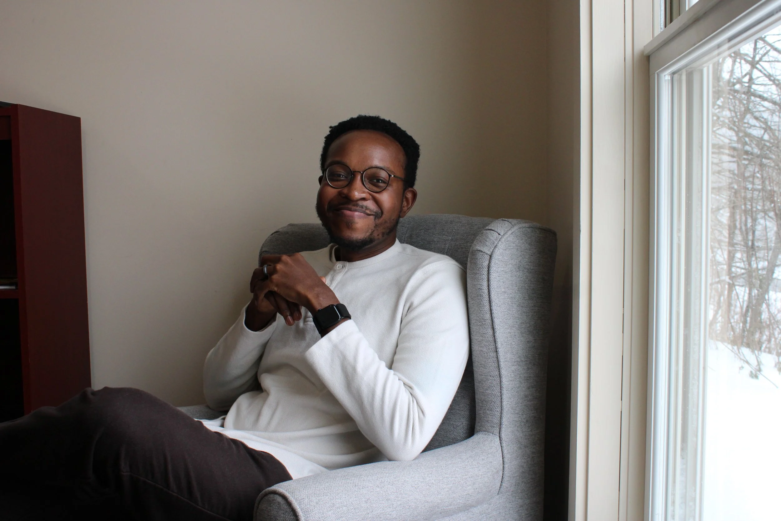 Olatunde Osinaike sitting in a gray chair.