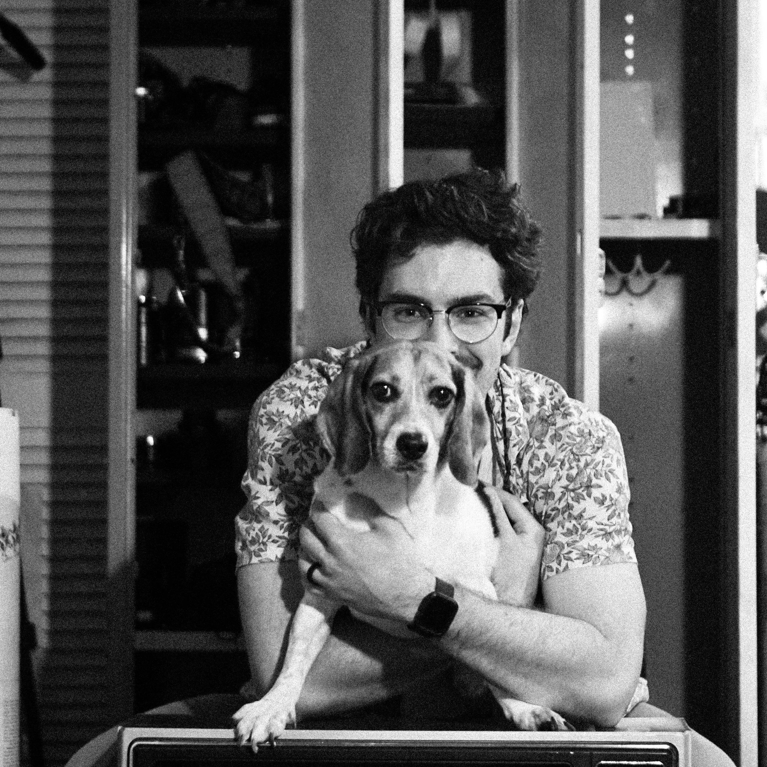 T.M. May sitting in front of a closet and holding a dog.
