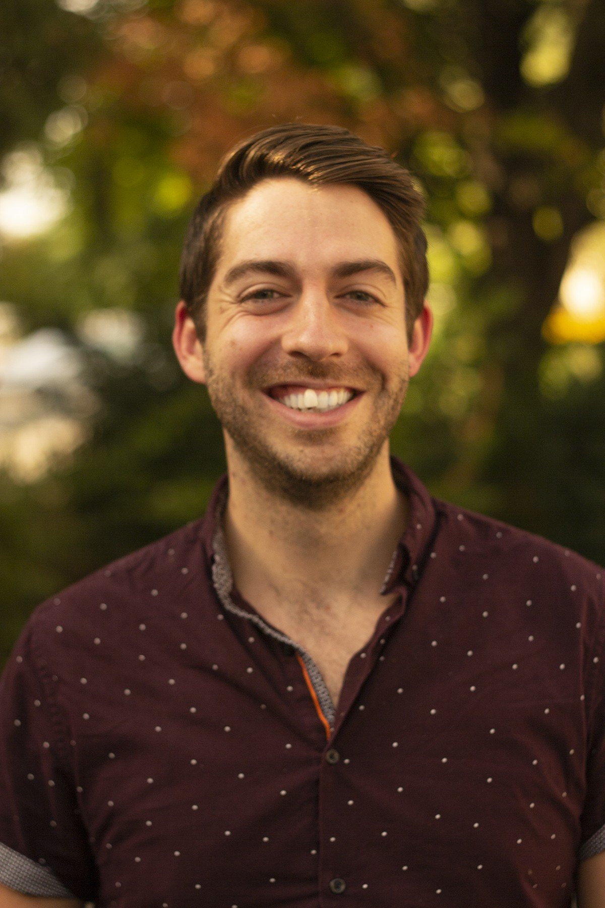 Adam Polaski standing in front of green trees.