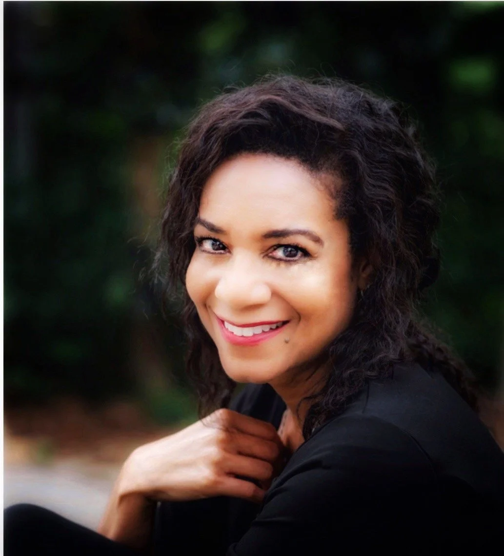 Ann Michelle Harris sitting in front of green trees.