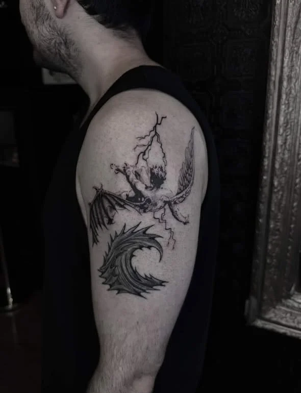Tattoo of a dragon, lightning, and a bird on a person's upper arm.