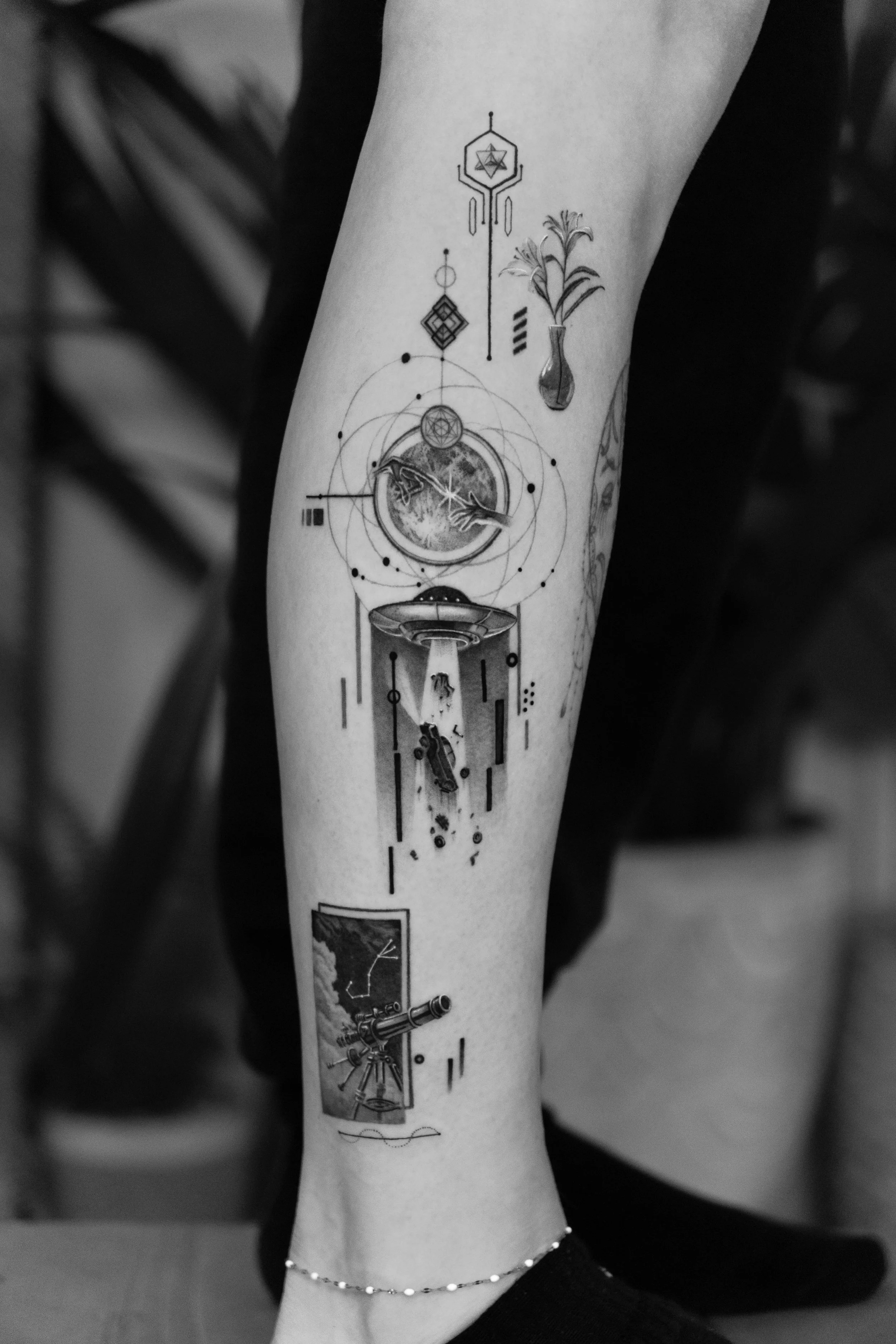 Black and white tattoo sleeve featuring celestial, astronomical, and scientific imagery including planets, a telescope, a UFO, a flower in a vase, geometric shapes, and various abstract and symbolic elements.