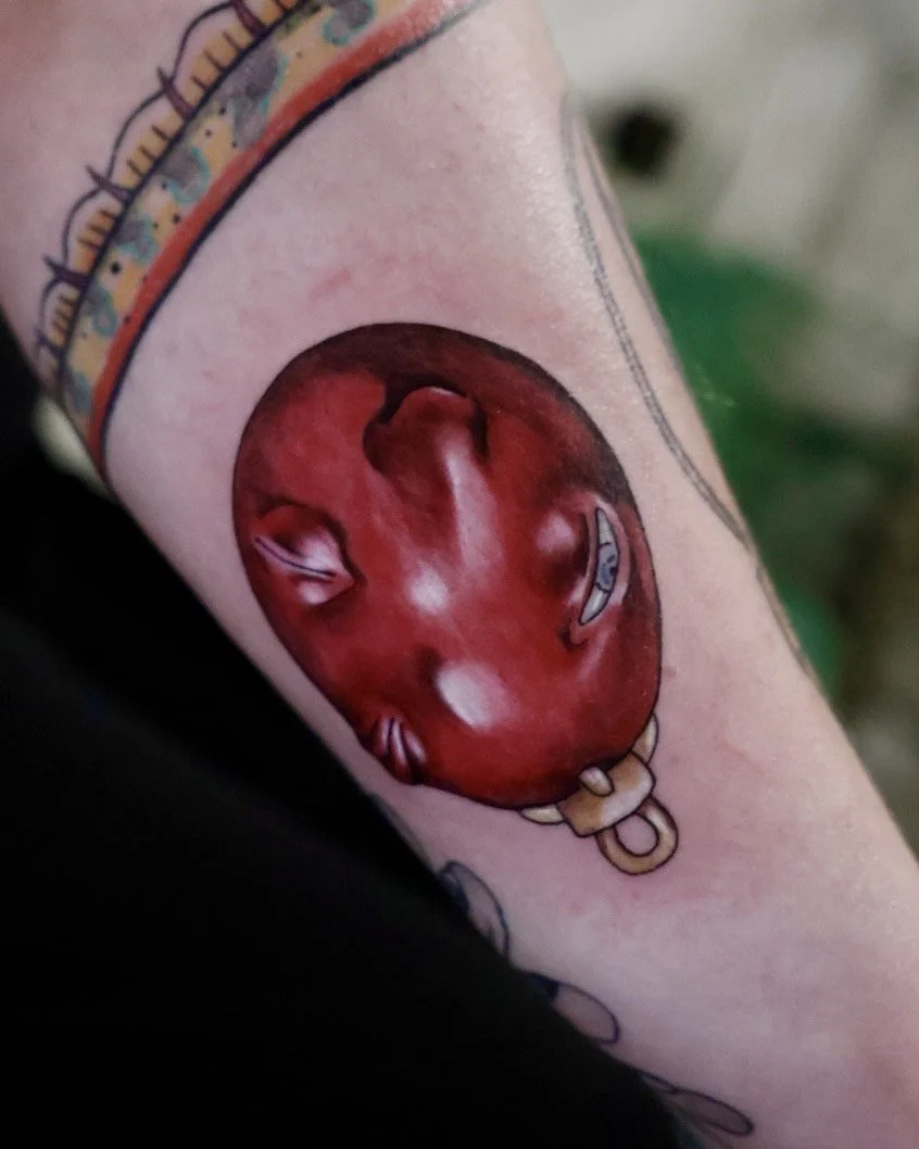 Tattoo of a baby wearing a gold chain.