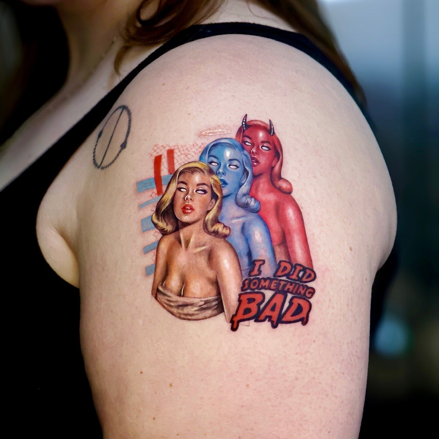 Tattoo of three stylized female figures with different skin tones and hair colors, with the phrase 'I did something BAD' on the shoulder.