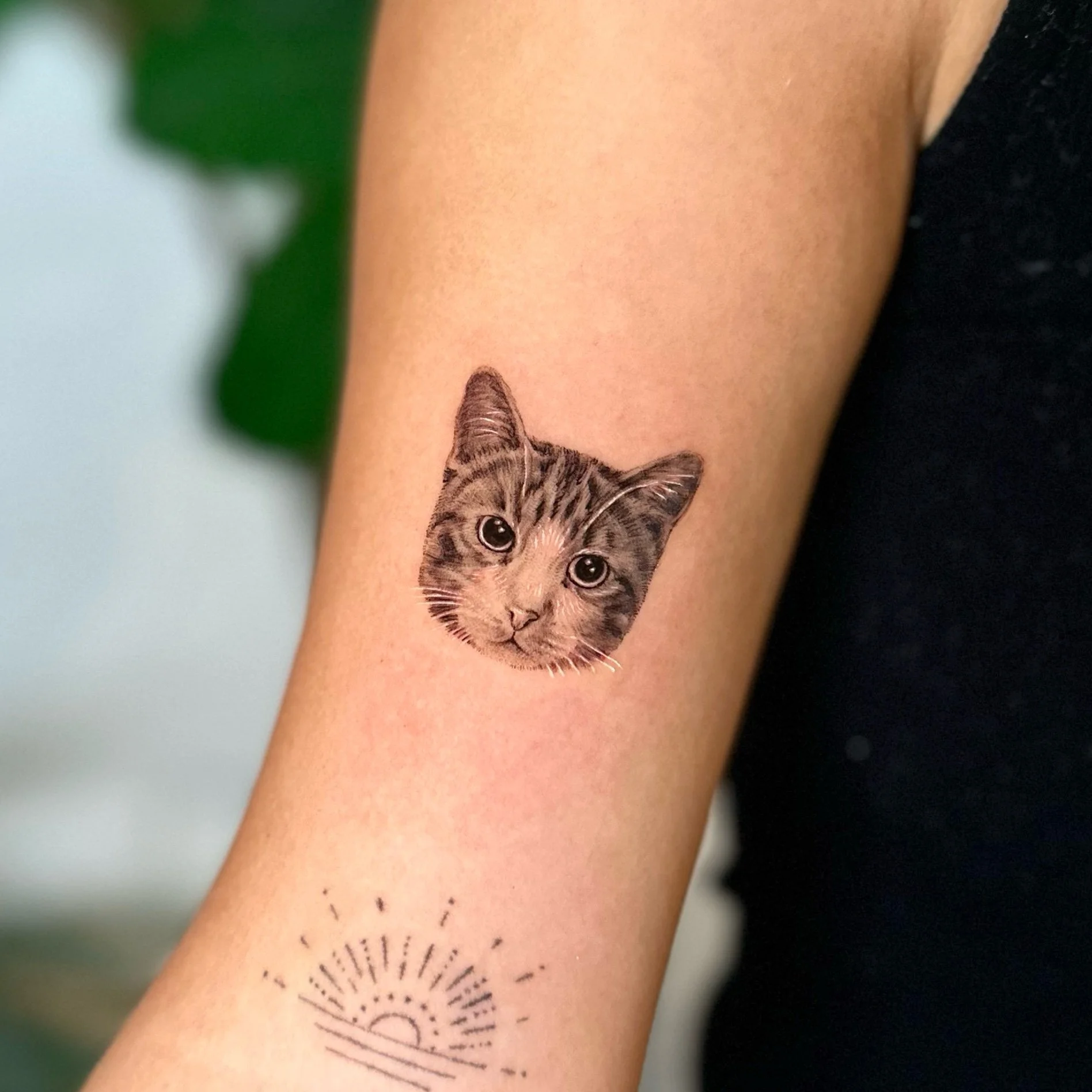 Temporary tattoo of a realistic cat's face on a person's forearm.