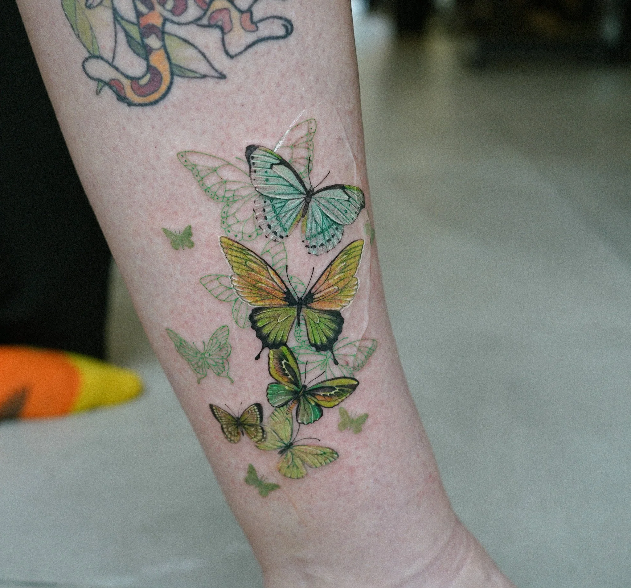 Tattoo of various colorful butterflies on a person's arm.