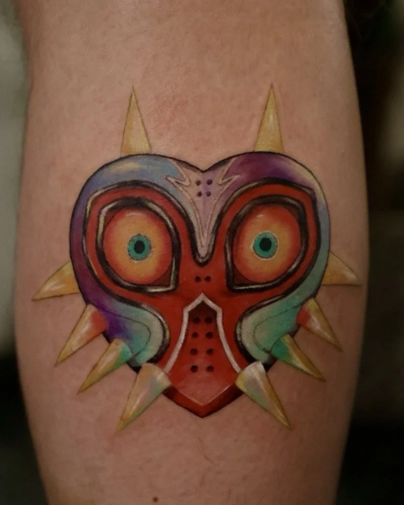 Colorful tattoo of a heart with eyes, surrounded by spiked sun rays.