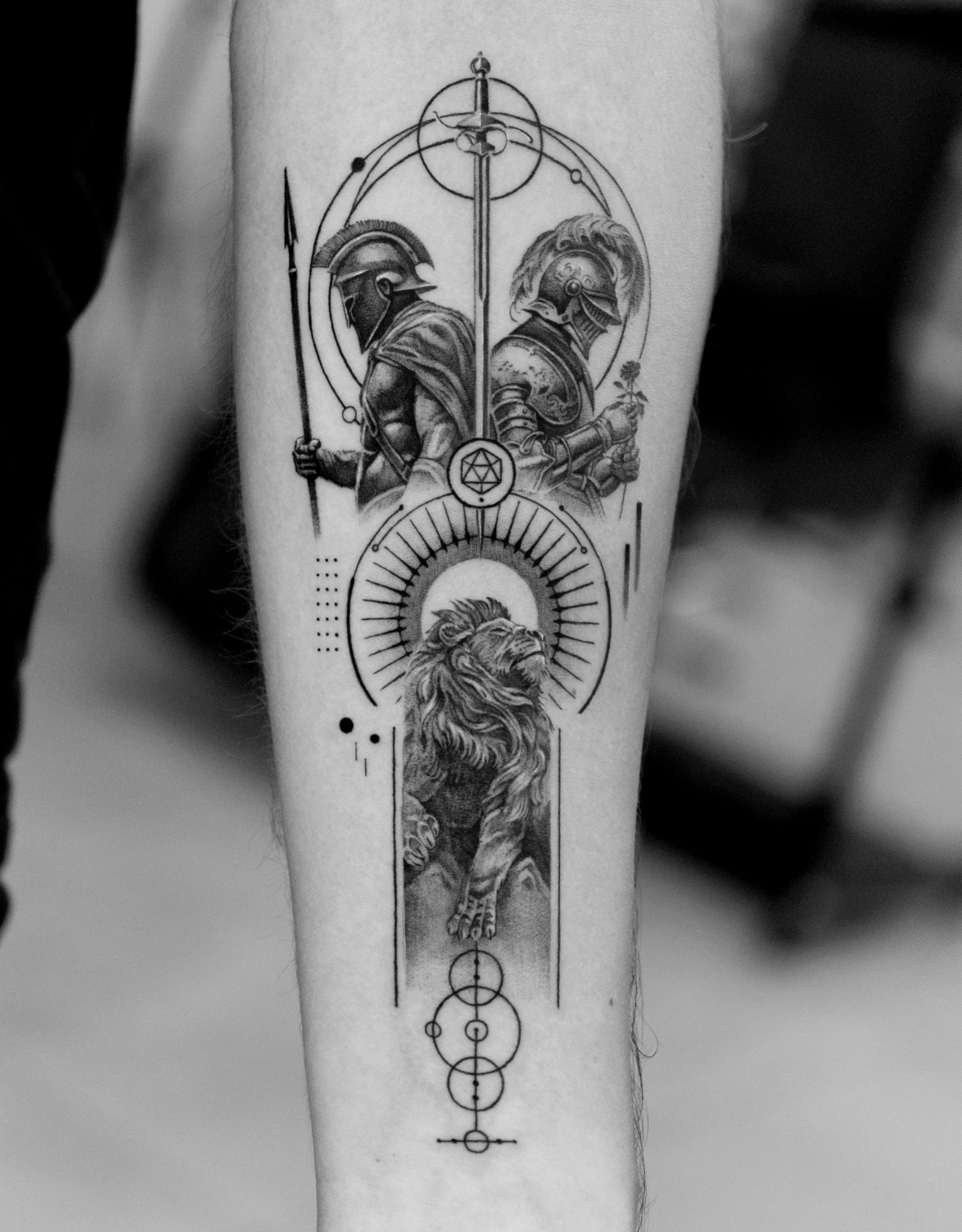 Black and white tattoo of two armored warriors back to back, holding weapons, with geometric and symbolic design elements, including a lion's head, circles, and lines.
