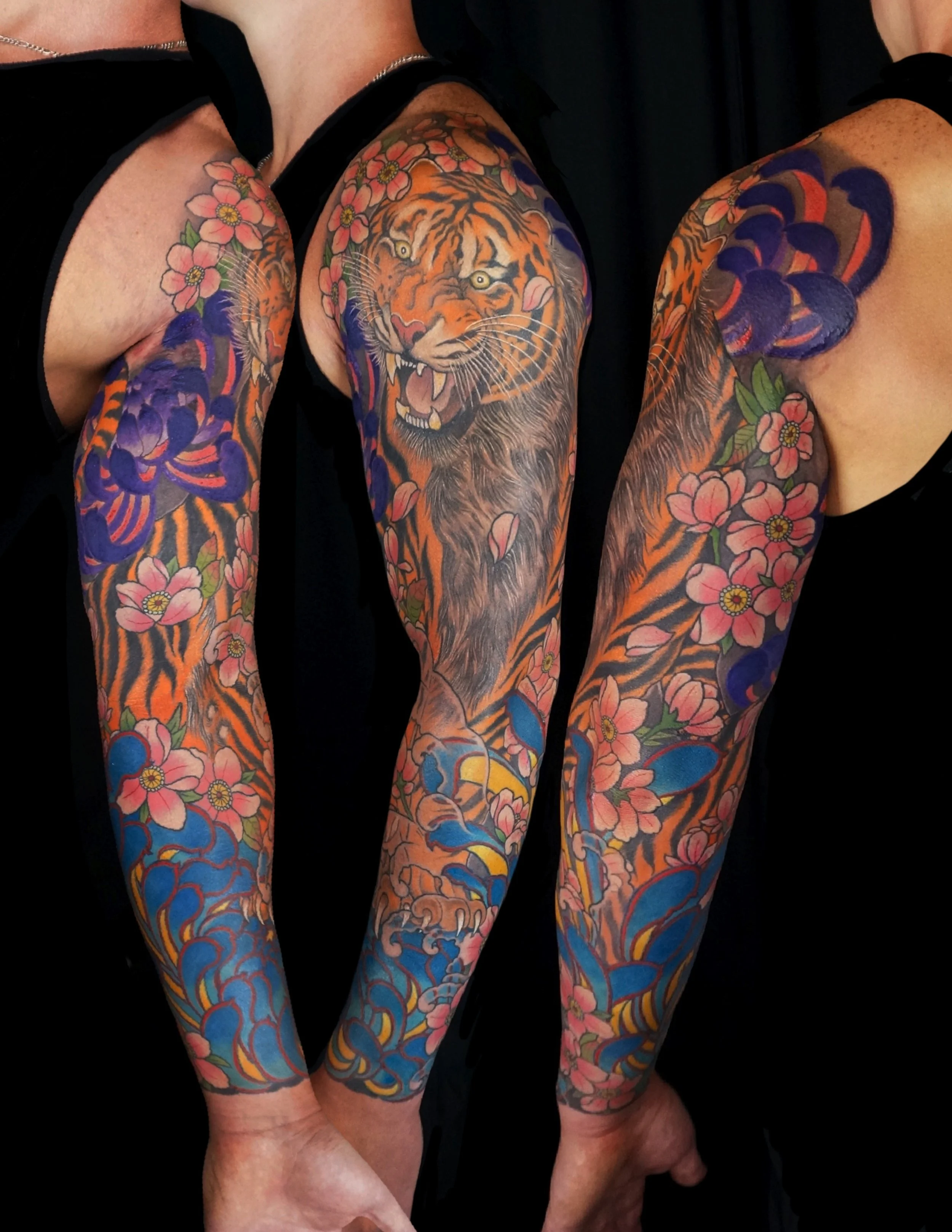 Colorful full sleeve tattoos of tiger faces, pink flowers, and swirling patterns on both arms.