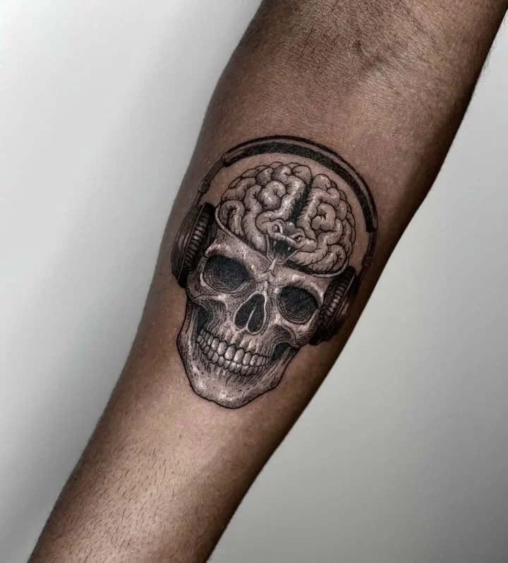 Tattoo of a human skull with a brain on top, wearing headphones.