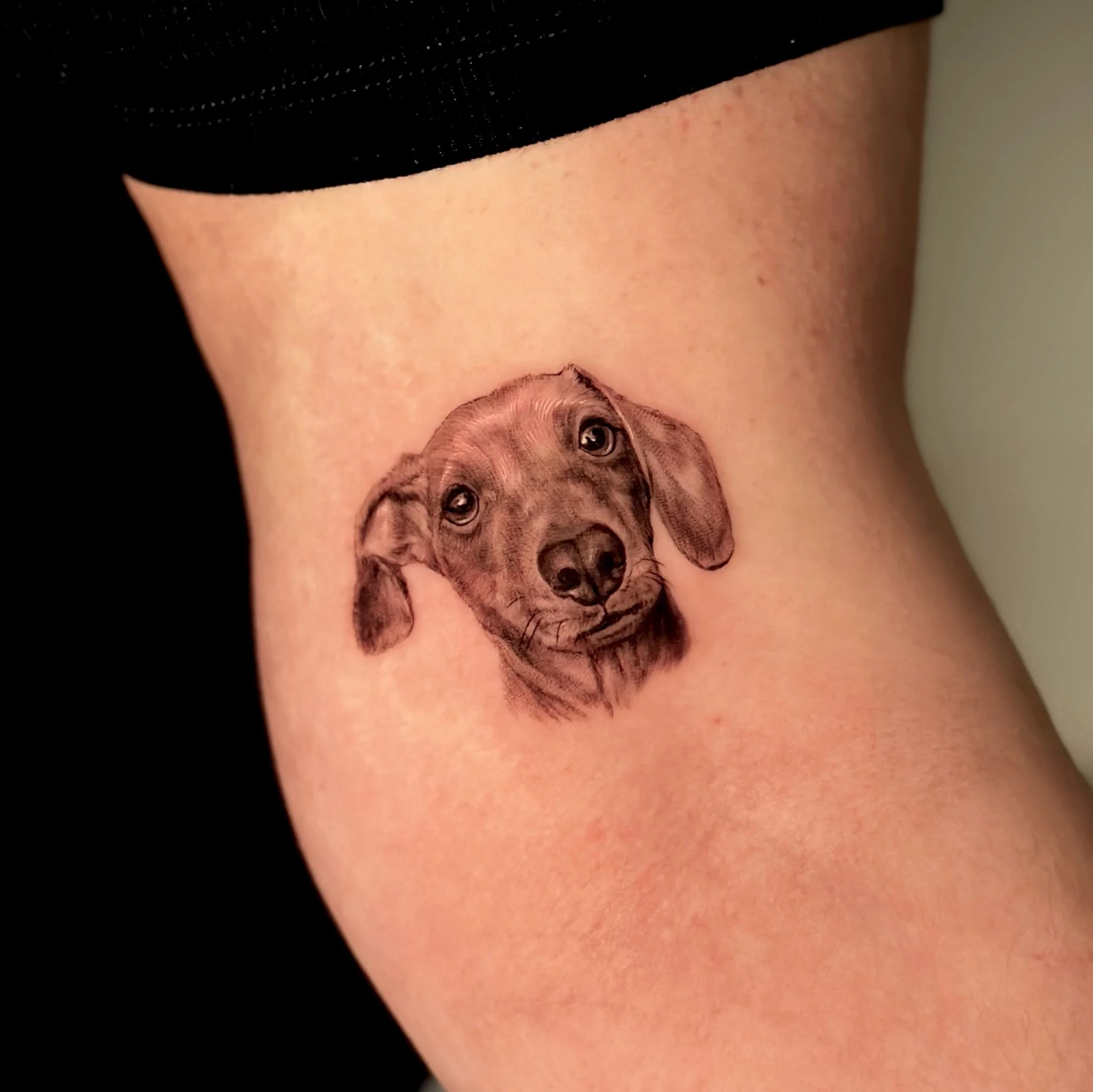 A realistic tattoo of a dog’s face on a person’s side waist area.