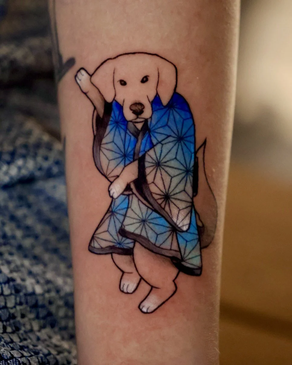 Tattoo of a dog dressed as a martial artist with one paw raised. The dog is wearing a blue kimono with geometric patterns.